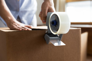 man applying packing tape to a box